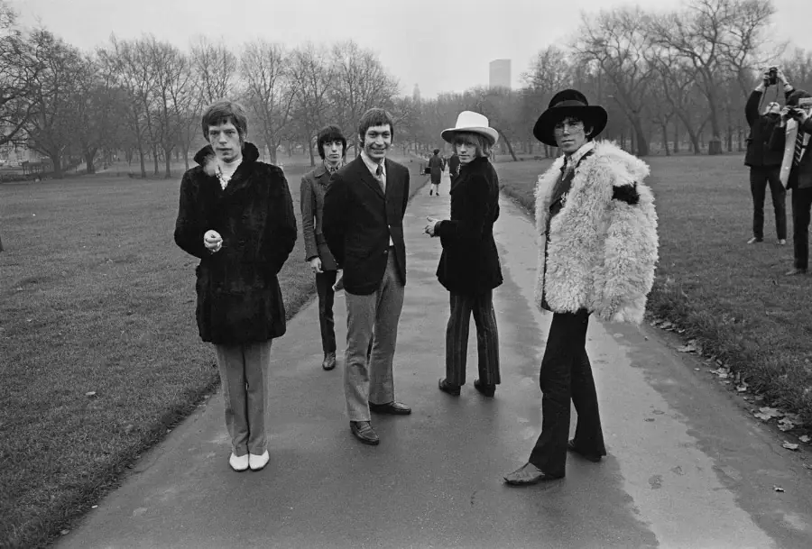 Five men in sharp coats on a park path, black and white