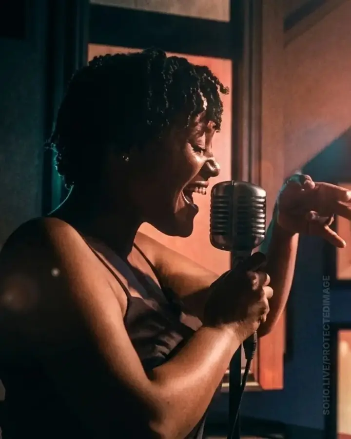 Riketté Genesis singing into a vintage microphone