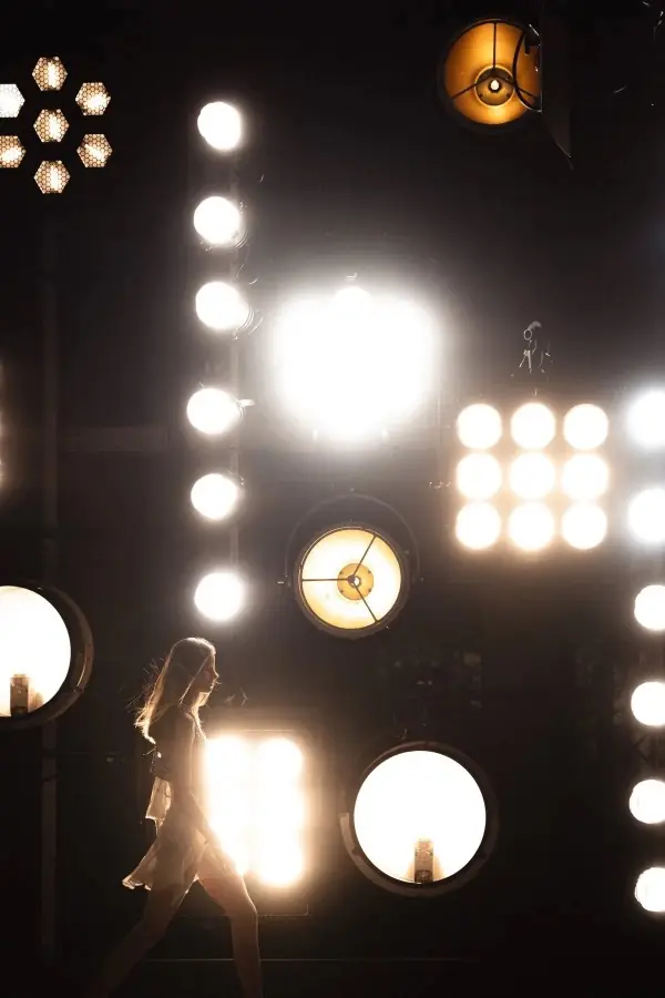 A wall of stage lamps with a figure crossing in front