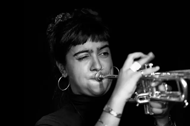 Olivia Cuttill playing trumpet, in black and white.